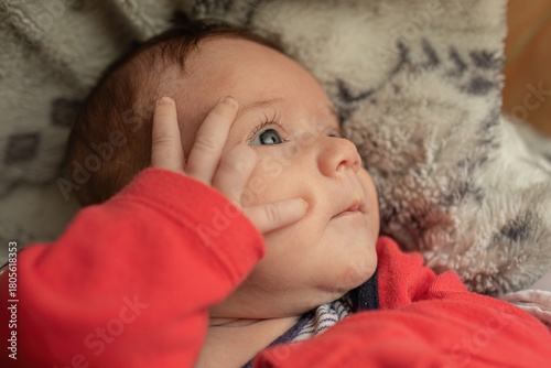 A closeup portrait of a baby lying on a cozy patterned blanket