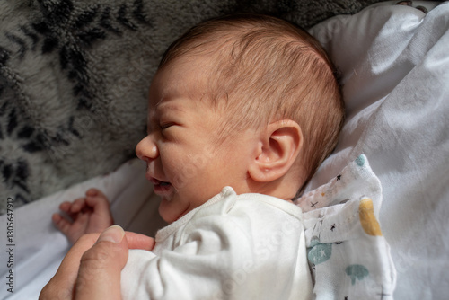 Crying Newborn Baby on soft blanket Held by a Parent