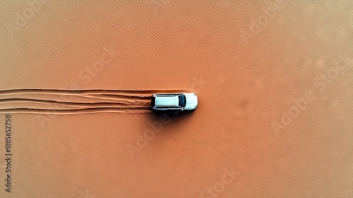 A white SUV drives across a desert landscape, creating tire tracks in the sand.