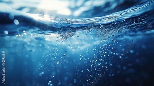 Fototapeta Naklejka Na Ścianę i Meble -  underwater view of sunlit water surface with rising bubbles, gentle ripples and a serene immersive blue mood