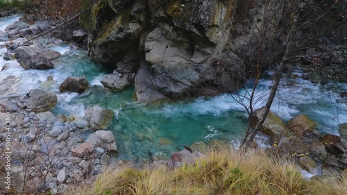 A powerful river with clear, turquoise water rushes through a rugged canyon. The scene captures the mesmerizing contrast of tranquility and raw natural power, with silky water flowing over and around 