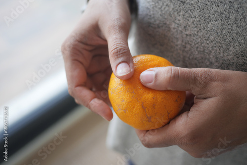 Person holding a fresh orange in a cozy indoor setting