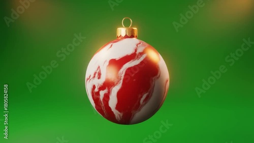 A festive Christmas ornament with a marble-like red and white design, suspended against a vibrant green backdrop, perfect for holiday decorations.