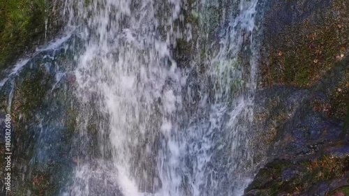 A close up, slow motion shot of a beautiful waterfall cascading over mossy rocks in the North Caucasus region of Russia. The footage captures the powerful and serene movement of the water, highlightin