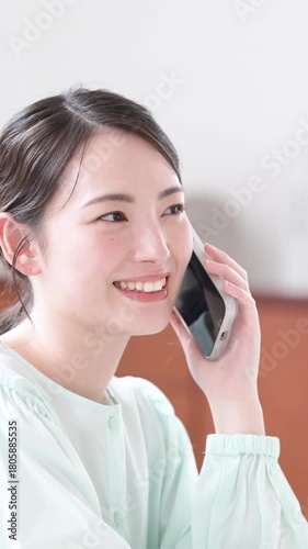 電話(スマホ)で明るく会話する 笑顔の女性　問い合わせや質問などのコンタクトをとるの縦動画