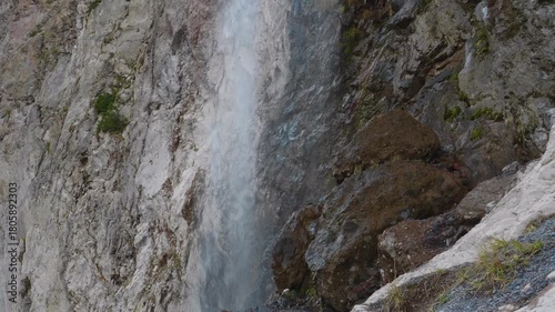 A view of a powerful waterfall cascading down a sheer rock face in the stunning mountainous landscape of the North Caucasus region of Russia.