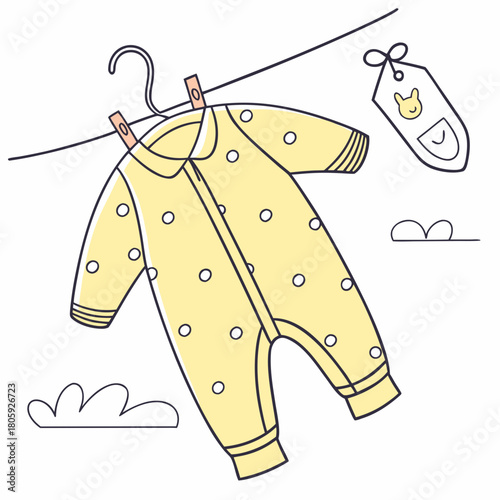 A charming yellow baby onesie with white polka dots hangs on a clothesline with a bib, isolated on a sweet scene of newborn essentials