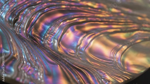 Macro close-up, slowly rotating mother of pearl texture reflecting intense iridescent holographic light shifts slow motion, colorful, abalone shell