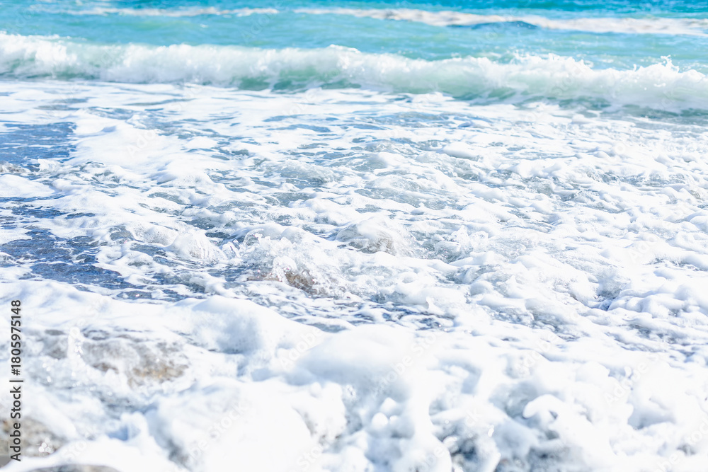 Obraz premium Foamy turquoise sea waves on the shore. Beautiful nature. Relaxation and tranquility. Background. Space for text.