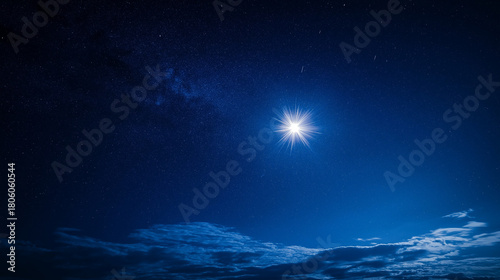 Bright star shining in deep blue night sky with clouds