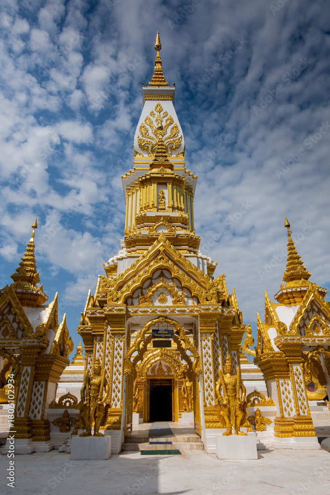 Fototapeta premium Phra That Ming Mueang Maru Nakhon stupa with ornate gold carvings, Buddha statues, and naga serpents. Sacred Thai temple showcasing intricate architecture, cultural heritage, and spiritual atmosphere