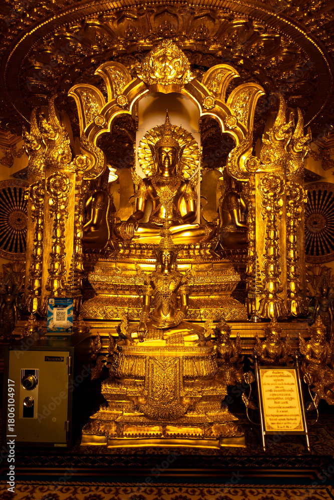 Fototapeta premium Phra That Ming Mueang Maru Nakhon stupa with ornate gold carvings, Buddha statues, and naga serpents. Sacred Thai temple showcasing intricate architecture, cultural heritage, and spiritual atmosphere