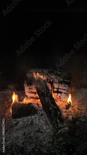 Wooden blocks are burned to prepare embers for a barbecue.