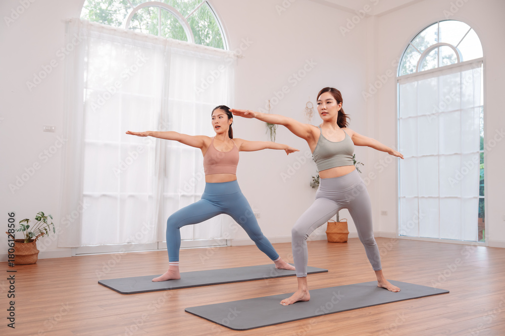 Obraz premium Wellness and healthy lifestyle. two Asian women exercising on yoga mats indoors. Focus on body balance, flexibility, posture, strength, and calm movement for mind body connection.