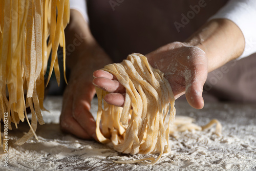 Caucasian female hands holding raw fettuccine noodles after drying