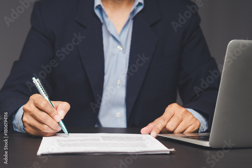 Businessman reviewing and signing document at desk.