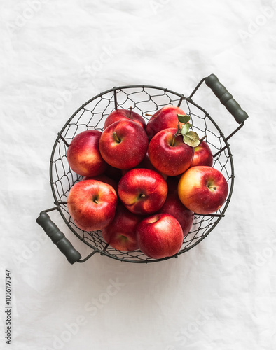 Ripe red autumn apples in a metal basket on the light background