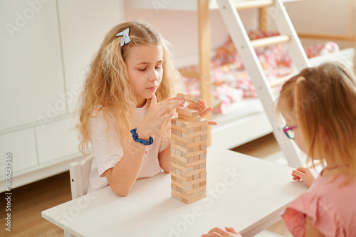 Фотография Girls playing block stacking game indoors