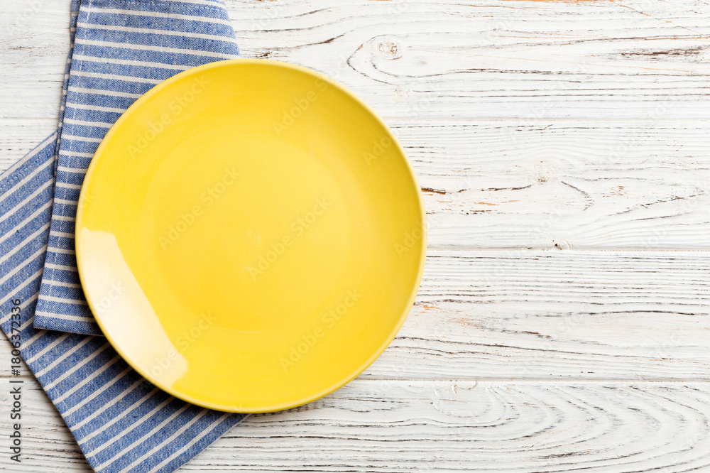 Obraz premium Top view on colored background empty round yellow plate on tablecloth for food. Empty dish on napkin with space for your design