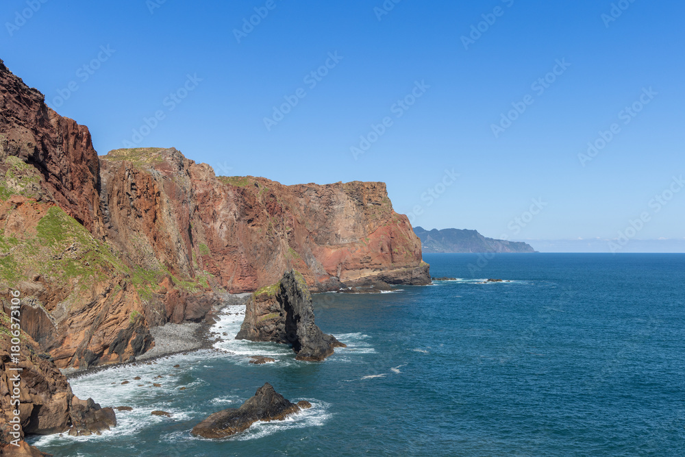 Fototapeta premium Coastal view of Sao Lourenco Point in Madeira with rugged cliffs, eroded rock pillars, and gentle surf, the warm tones of volcanic stone glowing in sunlight