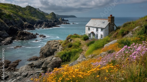 A Cornish seaside cottage with whitewashed walls slate roof and ocean views perched on a rocky coastline with