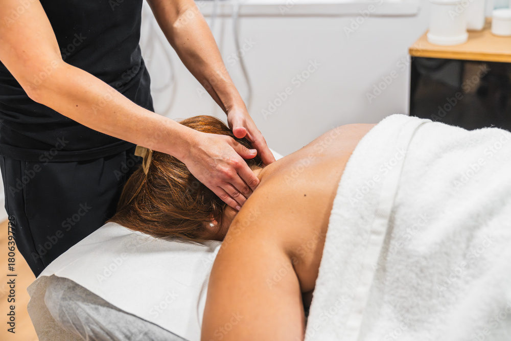 Obraz premium Wellness professional giving relaxing neck and shoulder massage to a person lying on a spa bed, promoting relaxation and stress relief