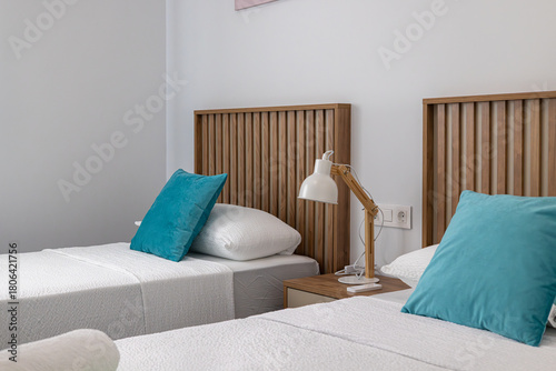 Modern twin bedroom with wooden headboards and teal pillows