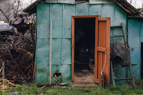 Obraz na plátně An old green rural shed with an open wooden door, showing a rustic interior