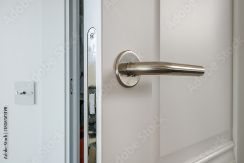 Modern door handle on white wooden door in interior. Knob close-up elements. Door handle, fittings for interior design