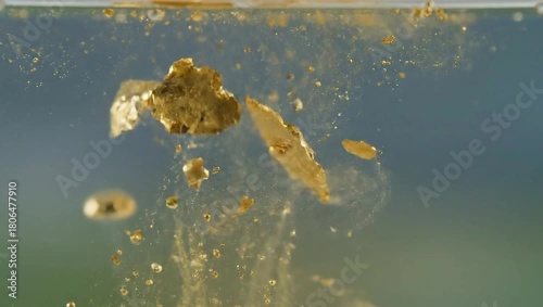 Golden Particles Swirling and Bubbling in Clear Water.