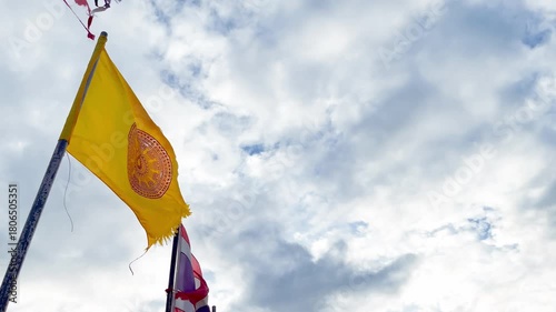 Weathered Thai Buddhist Flag and Thailand Flags Waving in Windy on Cloudy Sky Background at the Temple. Bueng Kan, Thailand. 03 NOV 2025, P.M.