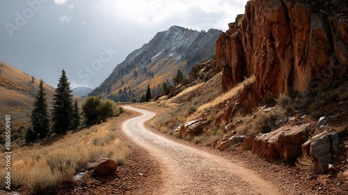 White gravel hiking trail winding up steep rocky hillside with vivid red and yellow stone formations under clear sky scenic desert mountain landscape