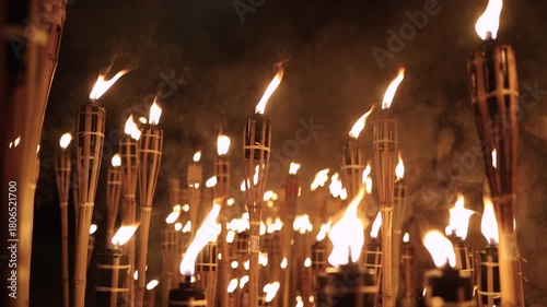 A captivating night scene of lit bamboo torches Warmflickering flames create a dramatic glow against the dark with soft bokeh lightsancient ritual cultural celebration spirit in a timeless spectacle