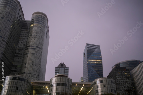 Glass and architecture shaping a compressed cityscape of finance with skyscrapers adding reflection and contrast to the urban landscape of the financial district in La Defense in Paris