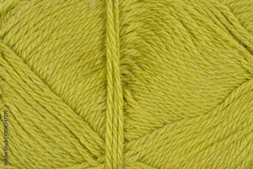 A close-up shot displays the textured surface of a ball of yarn in a vibrant olive-green color