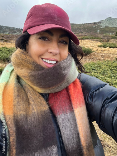 Beautiful young woman with autumn scarf and hat making selfie pictures outdoor 