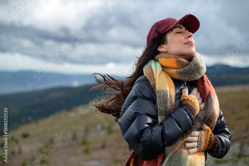 Relaxed woman breathing fresh air in the autumn mountain  and making breathing exercises 