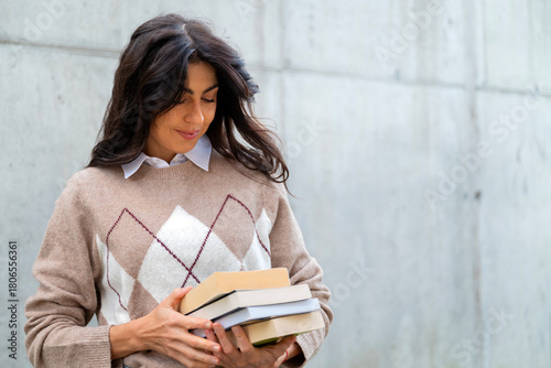 Beautiful young student woman standing on the street with books in the hands