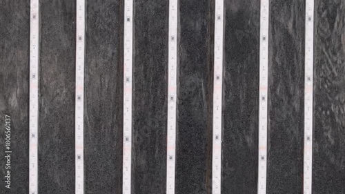 Black stone wall with water flowing down. Modern swimming pool or fountain with led lights