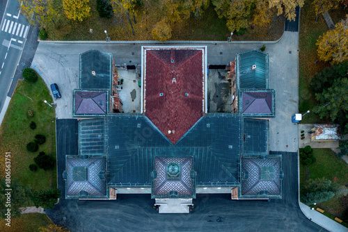 Aerial view of the Presidential Palace's symmetrical architecture, blending rich terracotta roofs with deep blues and greens, stands majestically amidst the surrounding parkland, Zagreb, Croatia.