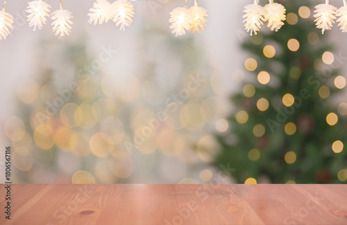 Wooden table with glowing pinecone string lights and blurred Christmas tree bokeh in background creating a warm festive holiday backdrop for seasonal decoration concepts cozy winter themes