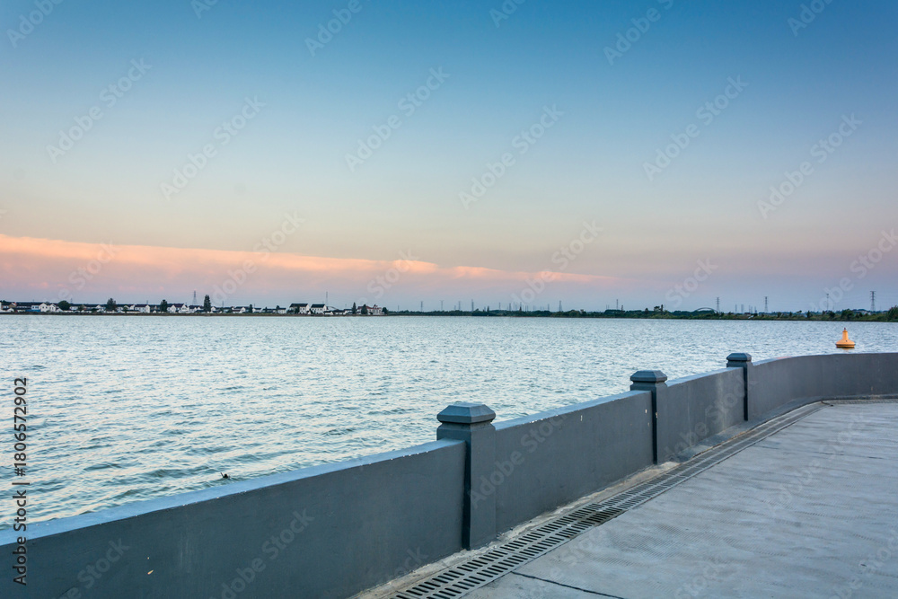 Obraz premium Serene Waterfront at Sunset: Capturing the Beauty of Nature's Transition