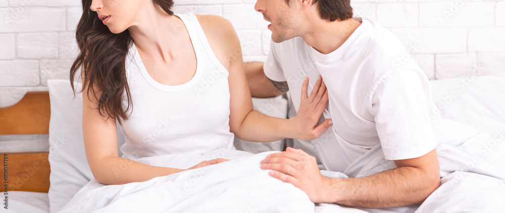 Fototapeta premium Marital crisis. Young woman refusing her husband in bed, making stop sign, panorama