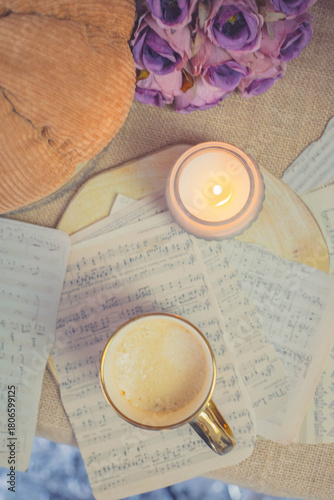 Warm latte in floral cup with candlelight and knitted textures, cozy autumn mood