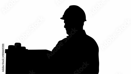 Silhouette of a construction worker wearing a hard hat standing near a dark object on a white background