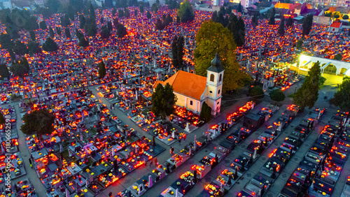 Aerial view of a sea of flickering lights illuminating the cemetery, highlighting the church's orange roof amidst the dark tombstones, Osijek, Osijek-Baranja County, Croatia.