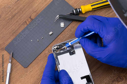 The master's hands use tools to disassemble the phone display