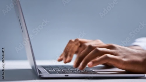 Close-up of hands typing on a laptop keyboard, blurred background, studio setting