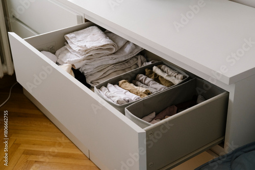 Drawer with neatly folded clothes in a white dresser, showcasing home storage and closet organization for tidy living spaces and an organized wardrobe.