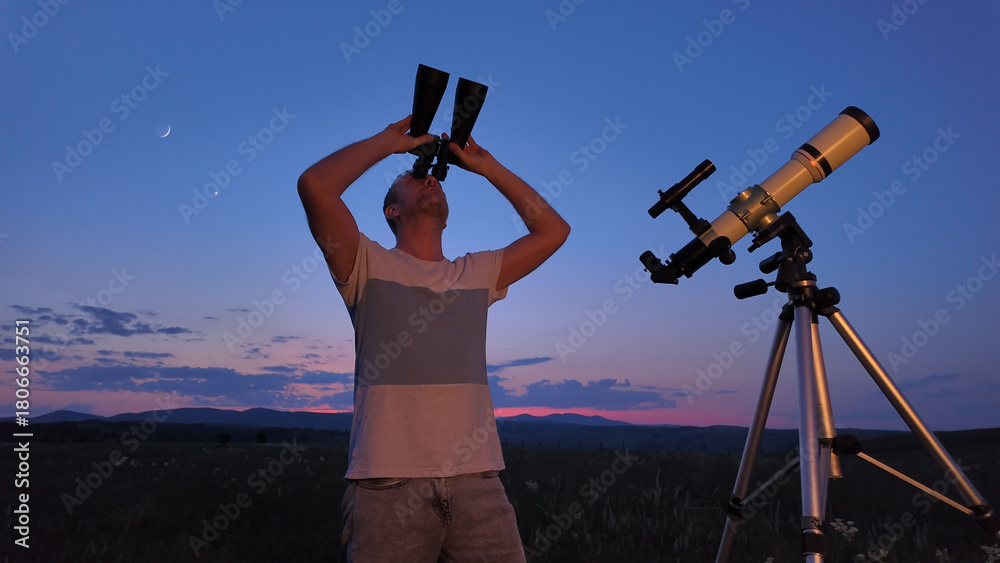 Fototapeta premium Amateur astronomer using telescope and binoculars for watching stars, Moon, planets and other celestial objects from a countryside field in nature.